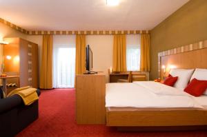 a hotel room with a bed and a flat screen tv at Pension Appartement Lanzer in Moosburg
