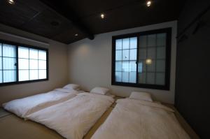 two beds in a room with two windows at Machiya Kaemon in Kyoto