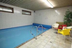 a swimming pool in a room with tables and chairs at Gästehaus Obermeier in Ruhmannsfelden