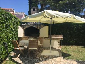 a table and chairs under an umbrella in a yard at Apartments Mladen in Njivice