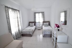 a living room with two beds and two windows at Pension Galini in Katapola