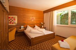 a bedroom with a bed and a desk and a window at Alpina Residence in Naturno