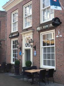 een bakstenen gebouw met een tafel en stoelen ervoor bij Hotel Marktzicht in Harderwijk