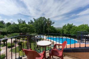 a balcony with chairs and a table and a pool at Hotel Fuente Las Piedras in Cabra