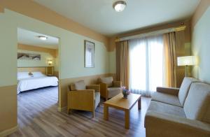 een hotelkamer met een bank en een bed bij Hotel Fuente Las Piedras in Cabra