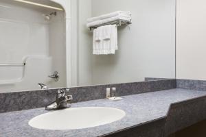 a white sink sitting under a mirror in a bathroom at Days Inn by Wyndham Edmundston in Edmundston
