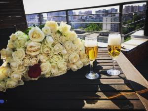 Um ramo de rosas brancas e dois copos de cerveja. em Mini-hotel People em Odessa