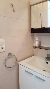 ein weißes Badezimmer mit einem Waschbecken und einem Spiegel in der Unterkunft Le Rallye Royan in Royan