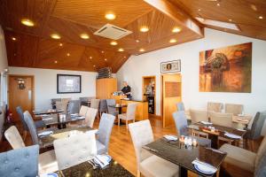 un restaurante con techos de madera, mesas y sillas en The Waterfront Seafront hotel and Bistro en Portpatrick