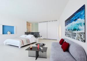 a white bedroom with a bed and a couch at Alti Santorini Luxury Suites in Megalochori +75 photos