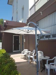 un ombrellone bianco su un patio con sedie e tavolo di Hotel Byron Light NUOVA GESTIONE 2024 a Riccione