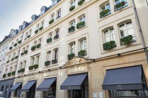 Un grand bâtiment blanc avec des plantes sur les fenêtres dans l'établissement Hôtel Bel Ami, à Paris