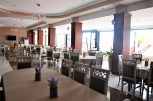 a dining room with tables and chairs and windows at Hotel Virginia in Durrës