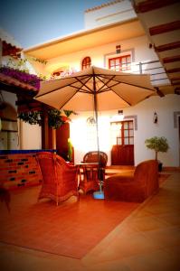 um pátio com 2 cadeiras e um guarda-sol em La Escondida Hostal em Sucre