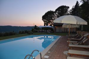 una piscina con sombrilla y sillas en Il Poggiolo di Parrano, en Parrano