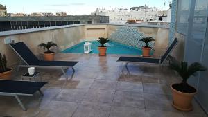 einen Balkon mit Stühlen und einen Pool auf dem Dach in der Unterkunft Apartamentos RG Suites Jardines de Murillo in Sevilla