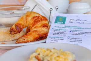 - un plat avec des croissants et un menu dans l'établissement Pousada Tímia, à Morro de São Paulo