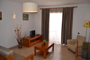 - un salon avec un canapé, une table et une télévision dans l'établissement Apartamentos Cabrita, à Olhos de Água