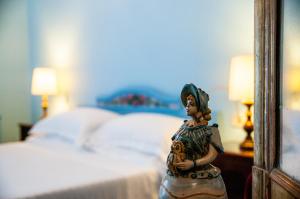 a figurine of a woman standing in front of a bed at Hotel Palladio in Giardini Naxos