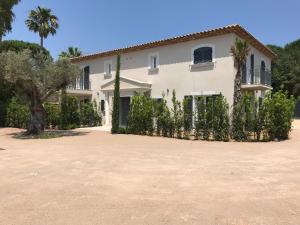 una gran casa blanca con árboles delante de ella en Windward en Saint-Tropez