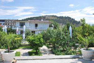 a white house with trees and white umbrellas at Blen Grand in Berat