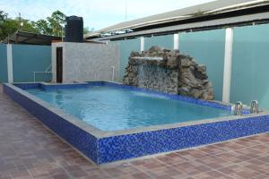 a large pool with a blue tile floor and a water fountain at Metro Hotel Couva in Couva