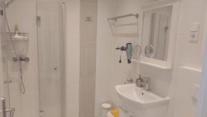 een witte badkamer met een douche en een wastafel bij Ferienhaus "Buchfink" in Berumbur