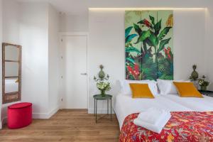 a bedroom with a large bed with a colorful painting on the wall at Apartamentos RG Suites Jardines de Murillo in Seville +68 photos