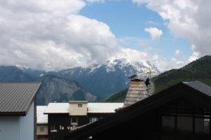 a bird sitting on top of a roof with a mountain at L'ours blanc in LʼHuez