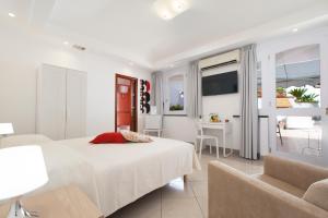 um quarto branco com uma cama e uma cadeira em San Nicola B&B em Castellammare di Stabia