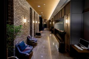 a hallway with chairs and a brick wall at Hotel East9 in Gangneung