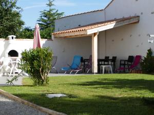 a patio with chairs and an umbrella on the side of a house at Ma Chaumiere in La Cotinière