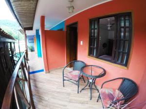 a patio with two chairs and a table on a balcony at Suítes Cantinho da Pedra in Abraão