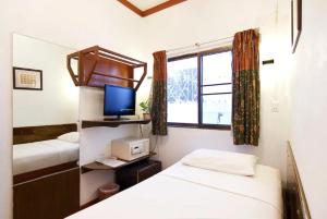 um quarto com duas camas e uma televisão e uma janela em Buakao Inn em Thongsala