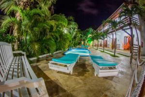 a swimming pool with benches and palm trees at night at Recanto do Barao Pousada in Jericoacoara