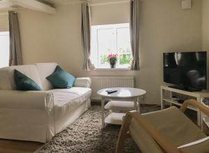 a living room with a white couch and a tv at Glemminge Bed and Breakfast in Glemminge