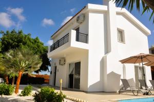 eine weiße Villa mit einem Pool und Palmen in der Unterkunft Villa Olivia, Coral Bay in Coral Bay