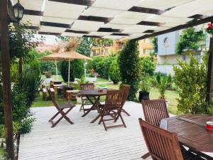un patio al aire libre con mesas, sillas y una sombrilla en Hotel Elmaz en Lozenets