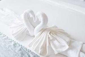 two white swan towels sitting on a bed at Lemonade Phuket Hotel -SHA Plus in Chalong