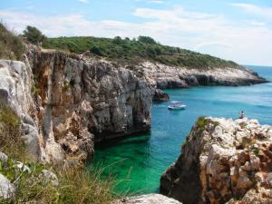 a boat in the water next to a rocky cliff at SubCastrum Apartments in Pula