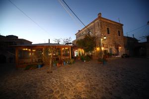 een lege straat 's nachts met een gebouw en bomen bij Pyrgos Houses and Restaurant in Avgonyma