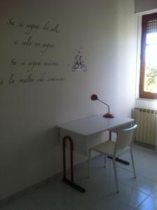 a desk and a chair in a room with writing on the wall at la casa per le tue vacanze in Milazzo