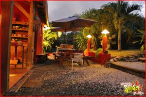 eine Terrasse mit einem Sonnenschirm, einem Tisch und Stühlen in der Unterkunft Sunset Surf Camp in Saint-François