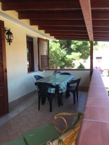 patio con tavolo e sedie sotto il portico di Green House a Porto Pino