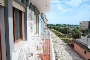 a row of white chairs sitting on the side of a building at Hotel del Mar in Sottomarina