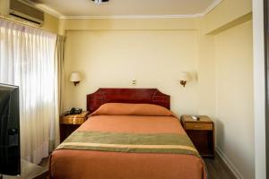 a bedroom with a bed and two night stands and a television at Hotel Diego de Almagro Antofagasta Express in Antofagasta