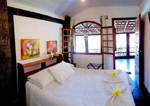 um quarto com uma cama branca com flores em Pousada Kafundó - Inhotim em Brumadinho