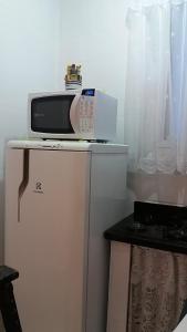 a microwave sitting on top of a refrigerator at Kitnet Guarujá - Pitangueiras - sem garagem in Guarujá