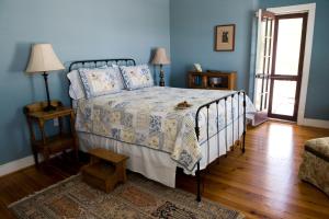 Cama en habitación con paredes azules y suelo de madera. en Hopkins Ordinary Bed, Breakfast and Ale Works, en Sperryville