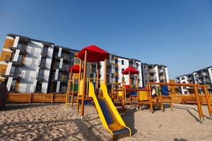 a playground with a slide in the sand in front of a building at Apartament Termalny Komfort 8.2 in Uniejow